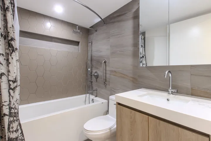 Bathroom with vanity, shower / bath combo with shower curtain, and tile walls
