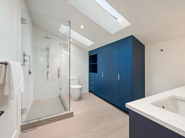 Full bath with double vanity, a stall shower, a skylight, recessed lighting, and lofted ceiling