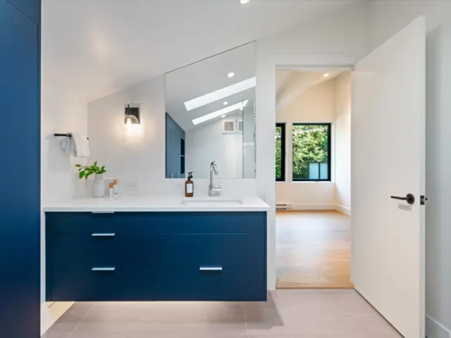 Bathroom with vaulted ceiling, vanity, a skylight, recessed lighting, and a baseboard radiator