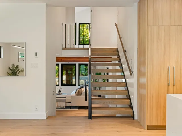 Stairway with healthy amount of natural light, wood finished floors, and a high ceiling