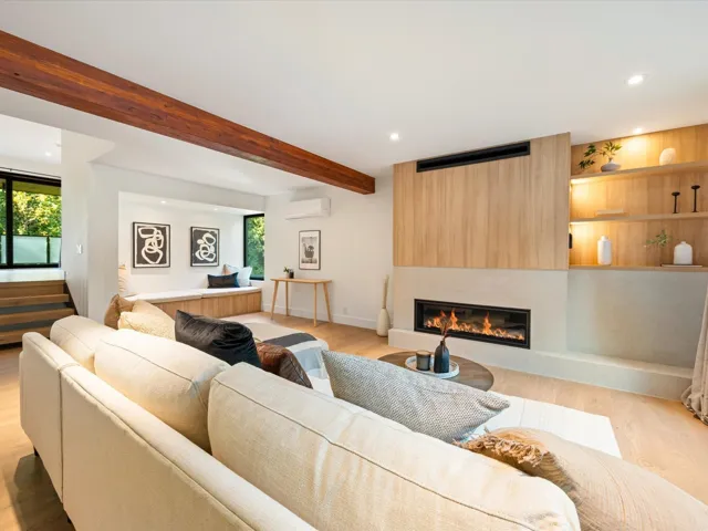 Living area featuring a large fireplace, light wood-style floors, beam ceiling, recessed lighting, and a wall unit AC