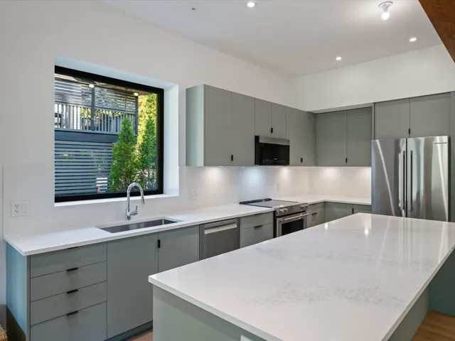 Kitchen featuring gray cabinets, stainless steel appliances, backsplash, a kitchen island, and light stone countertops