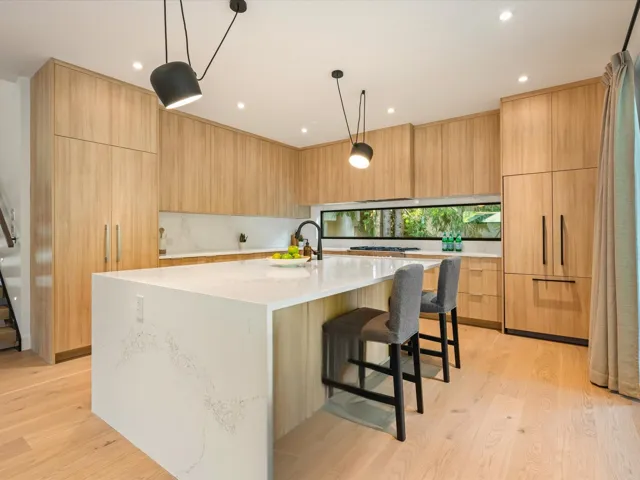 Kitchen featuring a kitchen bar, light wood-style floors, pendant lighting, a center island with sink, and recessed lighting