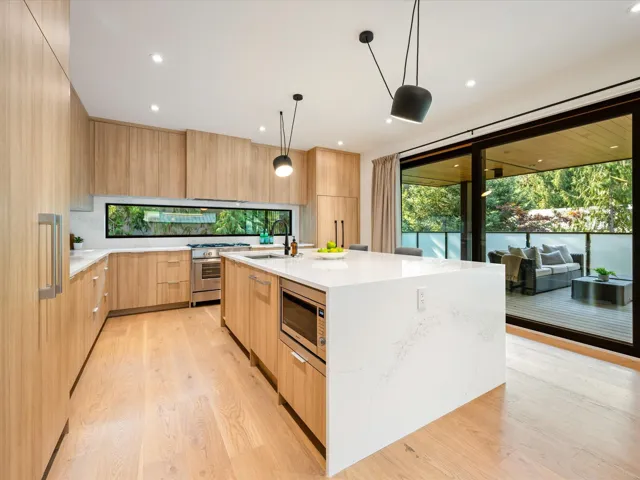 Kitchen featuring modern cabinets, light brown cabinetry, light stone counters, decorative light fixtures, and recessed lighting
