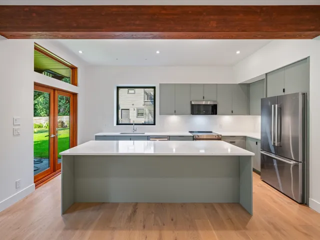 Kitchen with appliances with stainless steel finishes, a center island, tasteful backsplash, gray cabinetry, and light wood-type flooring