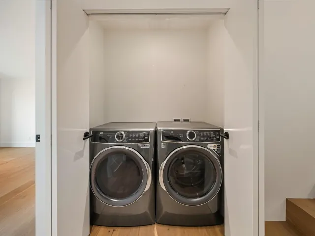 Washroom with wood finished floors and washer and clothes dryer