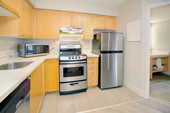 Kitchen with appliances with stainless steel finishes, light brown cabinetry, under cabinet range hood, and light tile patterned floors