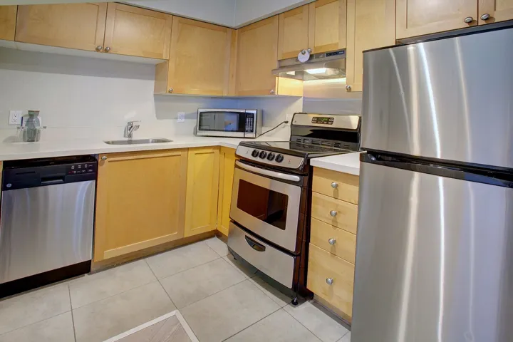 Kitchen featuring stainless steel appliances, light countertops, under cabinet range hood, and light brown cabinets