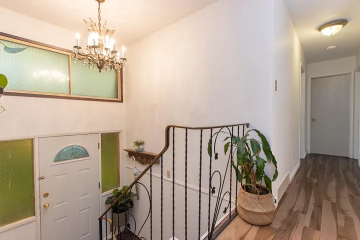 Foyer featuring baseboards, a notable chandelier, wood finished floors, and visible vents