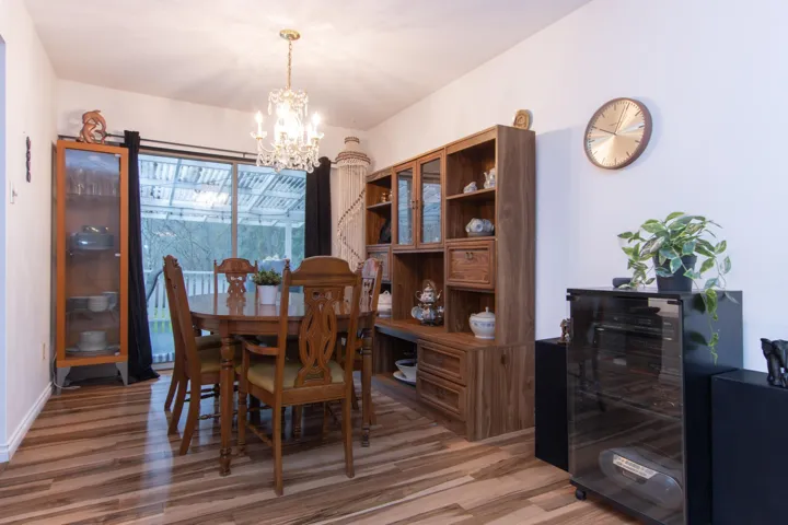 Dining space with beverage cooler, light wood-style flooring, baseboards, and an inviting chandelier