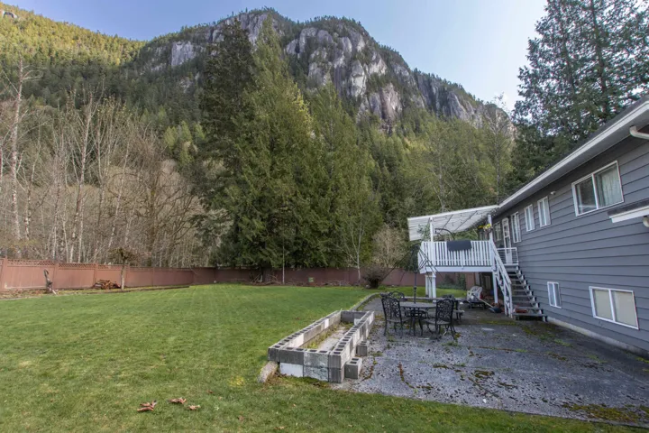View of yard featuring a deck with mountain view, a fenced backyard, a wooded view, stairs, and a patio