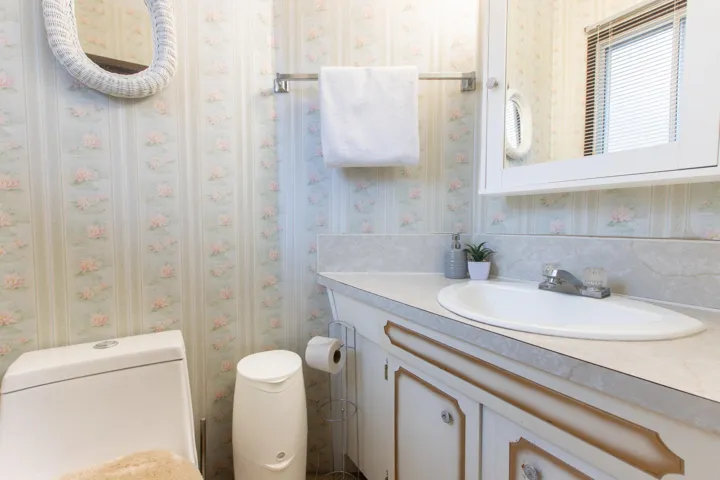 Half bathroom featuring wallpapered walls, toilet, and vanity