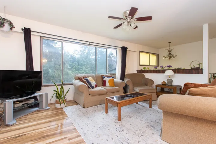 Living area featuring light wood finished floors and ceiling fan with notable chandelier