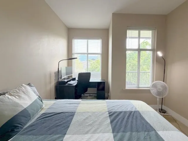 Neutral-toned walls complement two tall windows, each fitted with horizontal blinds, providing ample natural light