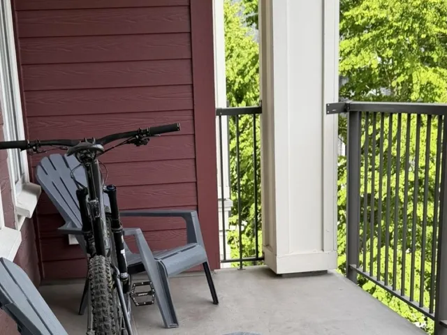 Private balcony featuring a concrete surface, durable metal railings, and a red horizontal siding exterior