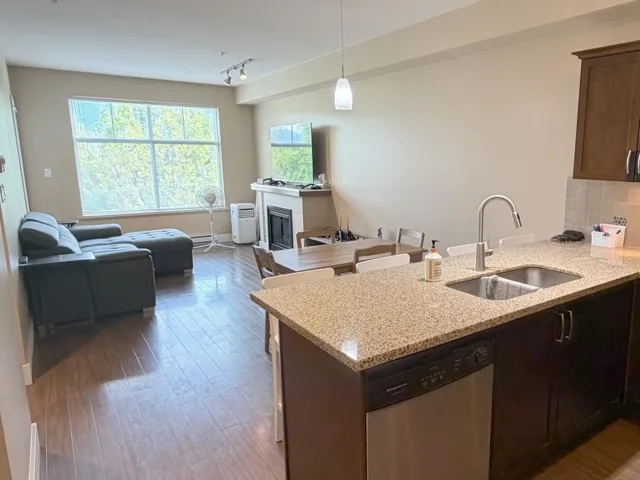 Open-concept living space featuring wood-finish flooring, a large window, and a built-in fireplace