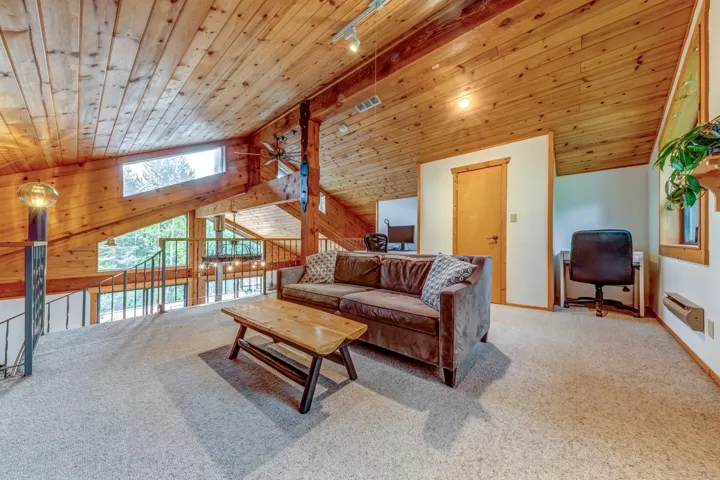 Living area featuring wooden ceiling, a ceiling fan, carpet floors, lofted ceiling, and a desk