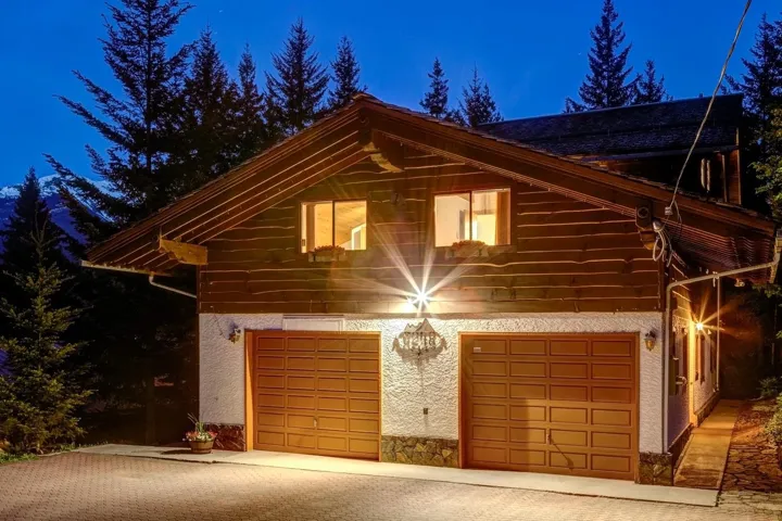Property exterior at night featuring an attached garage, stucco siding, and driveway