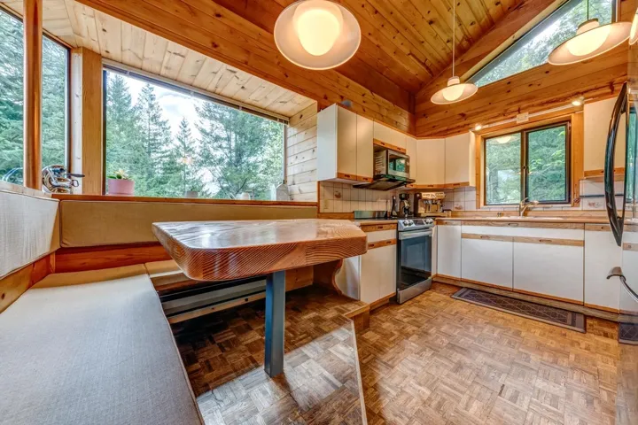 Kitchen featuring appliances with stainless steel finishes, a sink, lofted ceiling, white cabinetry, and wood ceiling