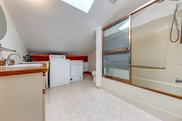 Washroom with washer / clothes dryer, light floors, and a skylight