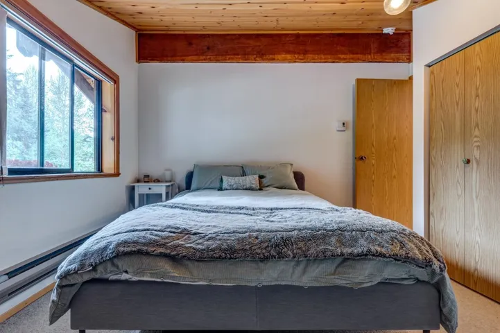 Bedroom featuring carpet floors, a closet, a baseboard radiator, beam ceiling, and wooden ceiling