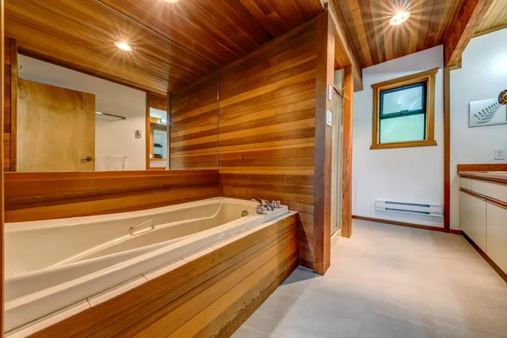 Bathroom featuring a baseboard radiator, wooden ceiling, a garden tub, vanity, and wood walls