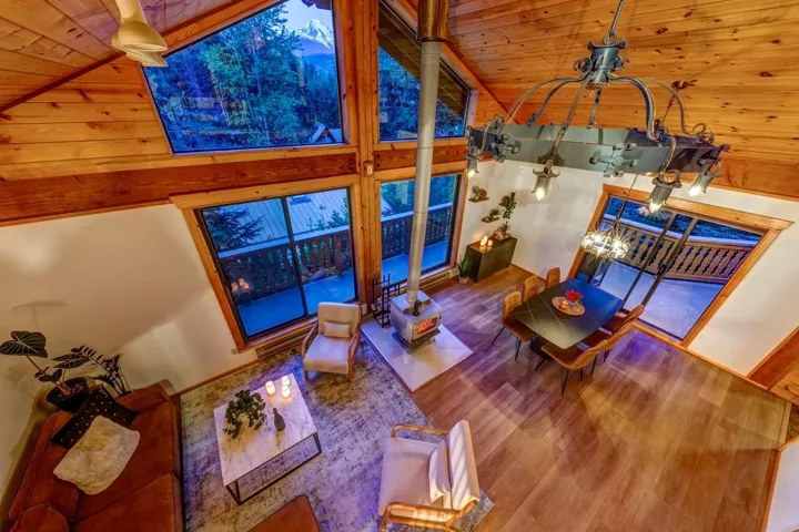 Living room featuring wood finished floors, lofted ceiling, wood ceiling, a chandelier, and ornate columns