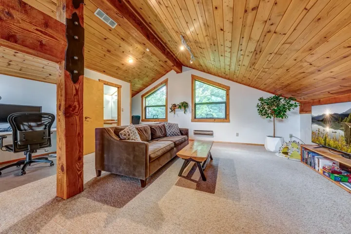 Living room featuring carpet flooring, an office area, wood ceiling, and baseboards