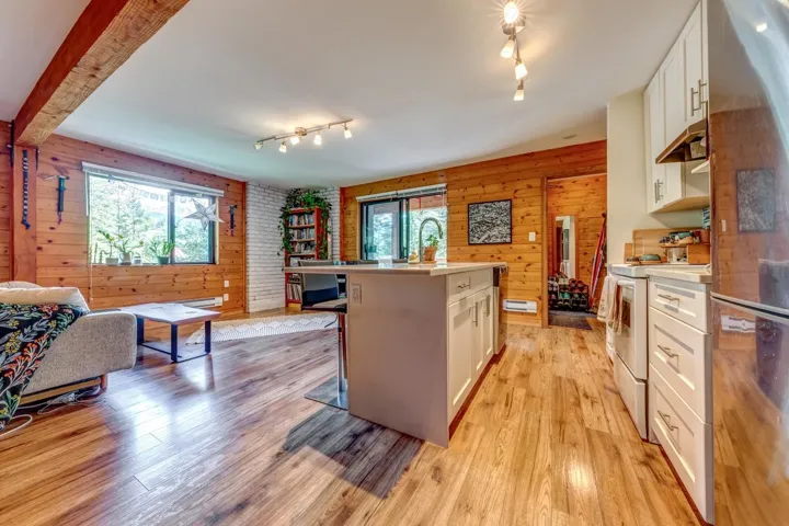 Kitchen with electric stove, rail lighting, light countertops, white cabinets, and wood walls