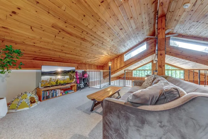 Living area with wooden ceiling, a skylight, carpet flooring, and vaulted ceiling