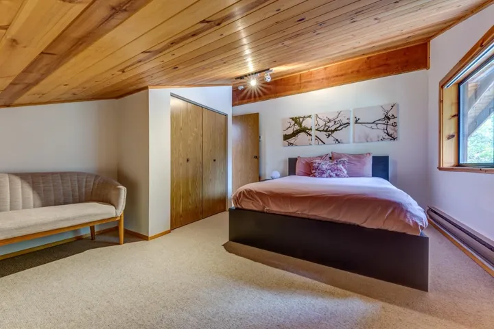 Carpeted bedroom with wooden ceiling, a baseboard heating unit, and a closet