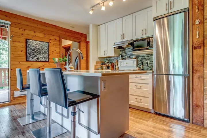 Kitchen featuring freestanding refrigerator, white cabinetry, light wood-type flooring, and wood walls