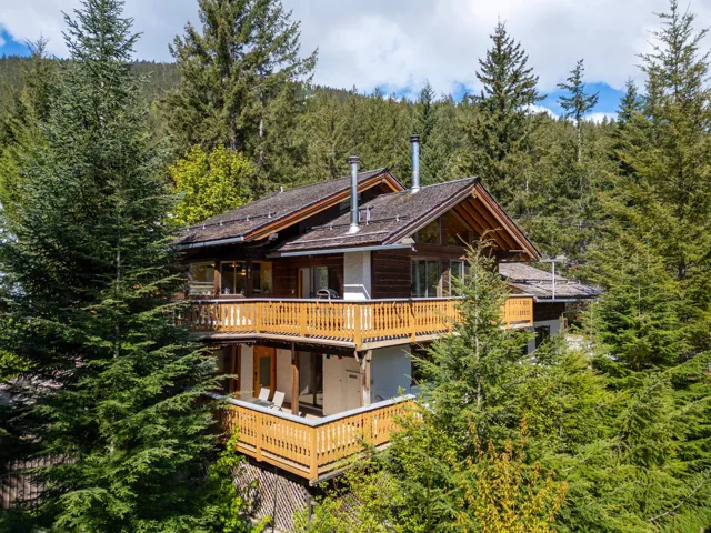 Rear view of house featuring a wooded view and a deck