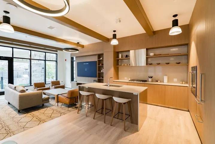 Kitchen featuring modern cabinets, decorative light fixtures, beam ceiling, a kitchen island with sink, and a kitchen bar