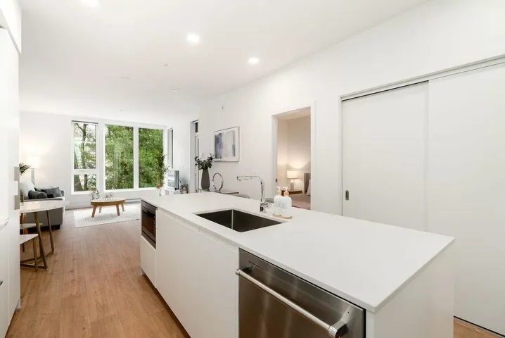 Kitchen featuring white cabinetry, modern cabinets, stainless steel appliances, a kitchen island with sink, and light wood-style flooring