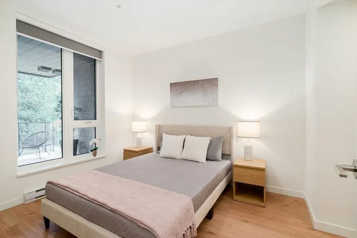 Bedroom with light wood finished floors and a baseboard heating unit