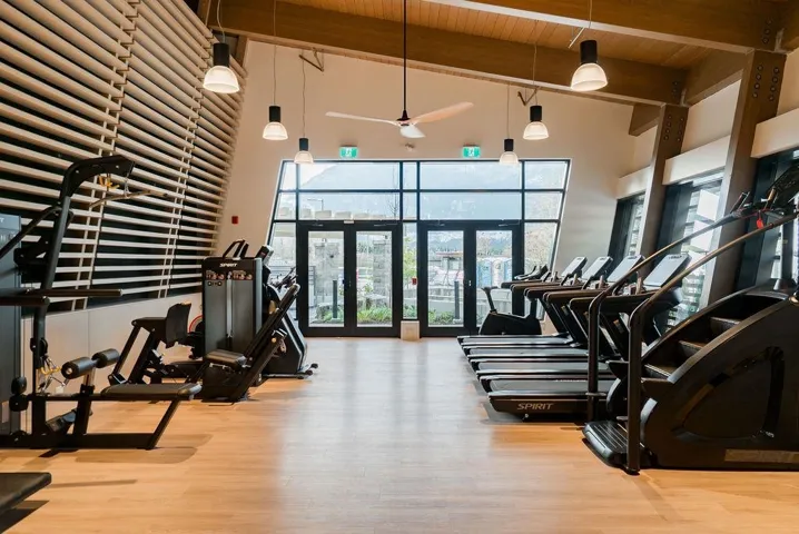 Workout area featuring a ceiling fan, a towering ceiling, and a wooden ceiling with exposed beams