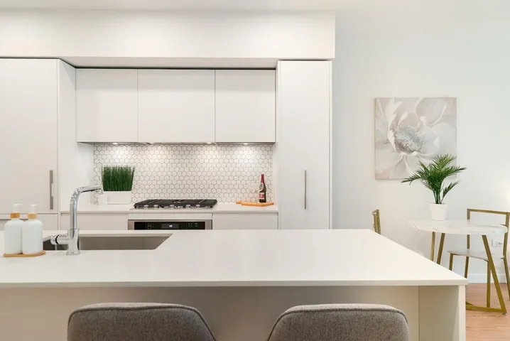Kitchen featuring white cabinets, modern cabinets, light stone counters, a kitchen bar, and tasteful backsplash