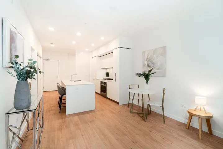 Kitchen with white cabinetry, modern cabinets, a kitchen island with sink, a breakfast bar area, and light wood-style floors