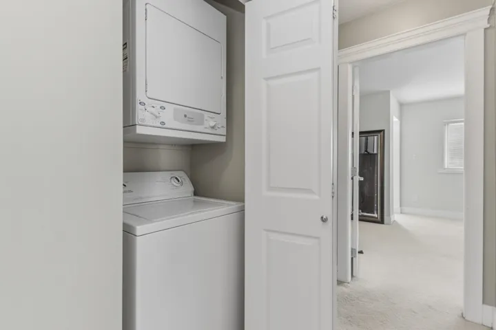 Dedicated laundry closet featuring a white stacked washer and dryer unit
