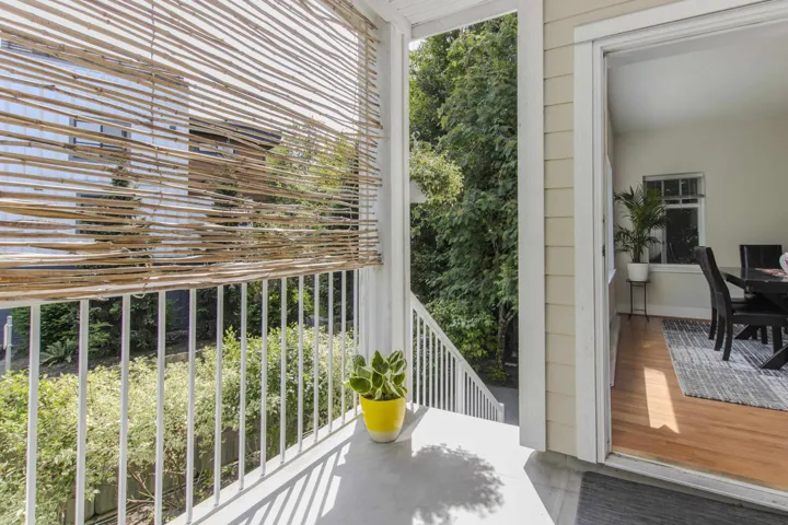 Outdoor balcony with a bamboo shade, white railing, and a durable concrete floor