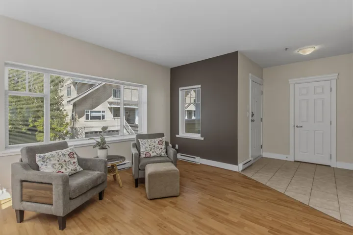 Bright living area featuring wood-finish flooring, a large multi-pane window, and a contrasting accent wall