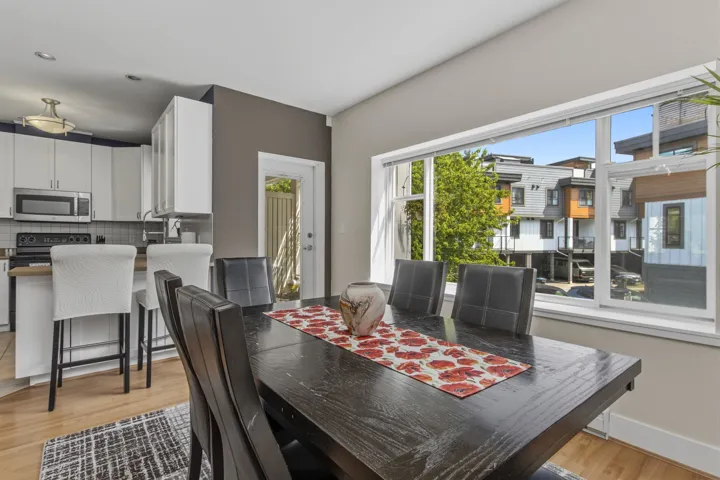 Open-concept dining area featuring wood-finish flooring and a large window