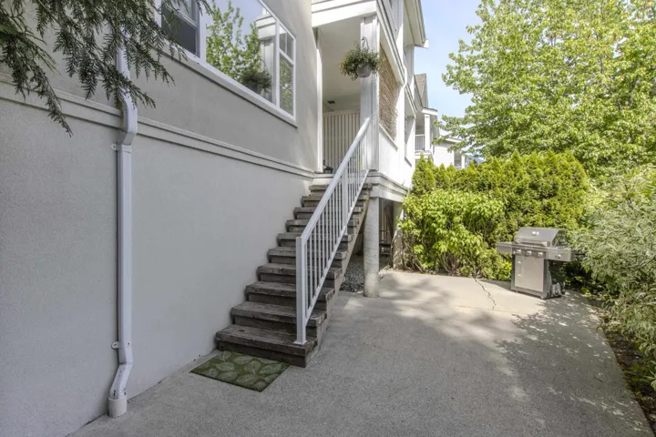 Exterior stucco finish with a ground-level concrete patio, featuring a multi-story structure with white railings and an outdoor staircase