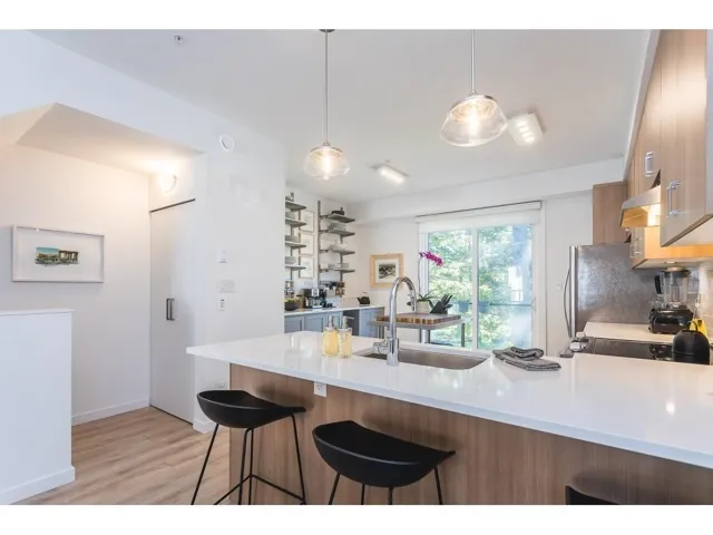 Kitchen featuring modern cabinets, wood finish cabinets, a kitchen breakfast bar, a peninsula, and light stone counters