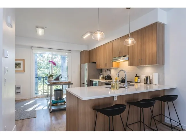 Kitchen with a peninsula, wood finish cabinets, a kitchen breakfast bar, and light stone counters
