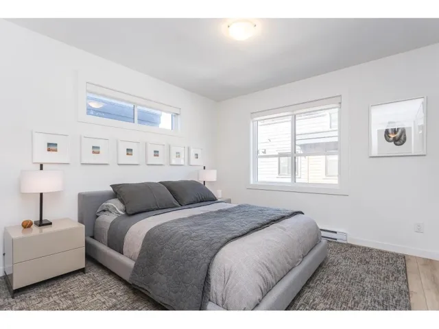 Bedroom with multiple windows, baseboard heating, and wood finished floors