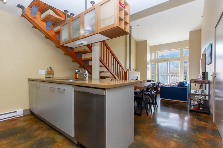 Kitchen featuring glass insert cabinets, concrete floors, open floor plan, dishwasher, and a sink