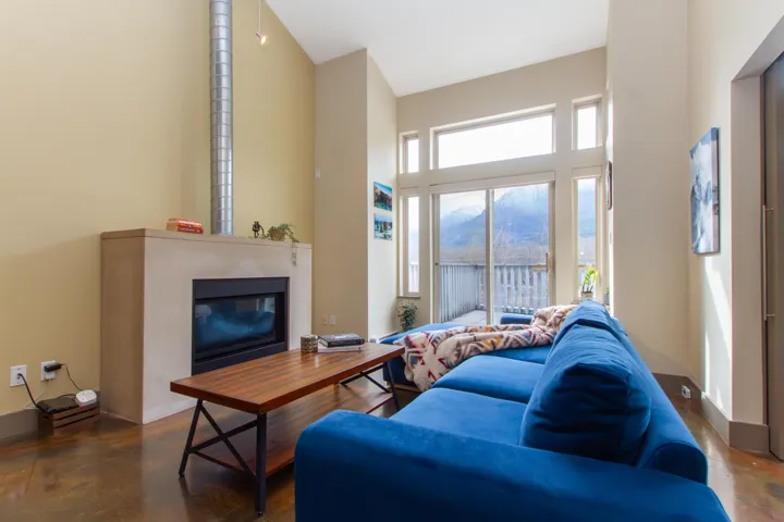 Living room featuring baseboards, a high ceiling, concrete flooring, and a glass covered fireplace