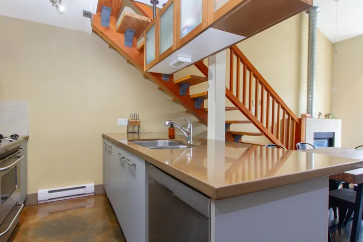 Kitchen featuring modern cabinets, a sink, a baseboard heating unit, finished concrete flooring, and stainless steel appliances